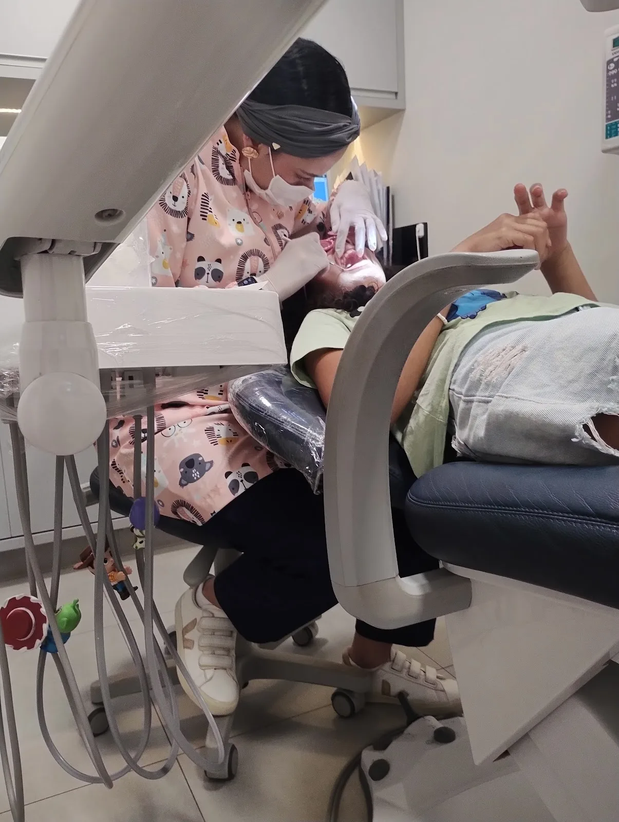 Odontopediatra da Clinisul atendendo uma criança com jaleco infantil